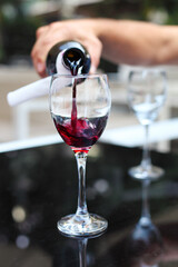 Pouring red wine from bottle into the wineglass