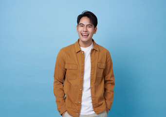Happy laughing young handsome southeast Asian man isolated on blue studio background.