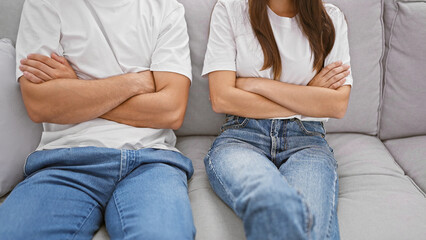 A man and woman sitting apart on a couch, showcasing tension and relationship problems in an indoor...