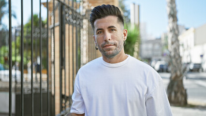 Young hispanic man looking to the camera with serious expression at street