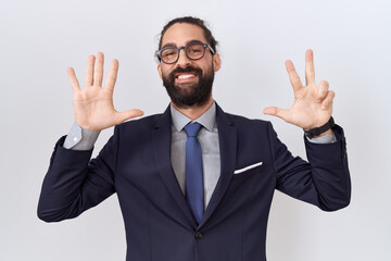 Hispanic man with beard wearing suit and tie showing and pointing up with fingers number eight while smiling confident and happy.