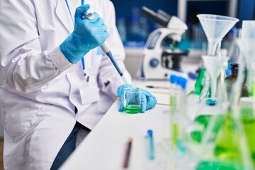 Young bald man scientist pouring liquid on test tube at laboratory