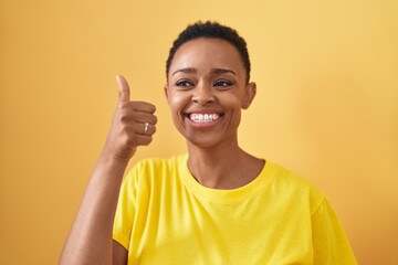 African american woman smiling confident doing ok sign with thumb up over isolated yellow background