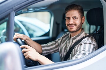 Hispanic man with beard driving car looking positive and happy standing and smiling with a confident smile showing teeth