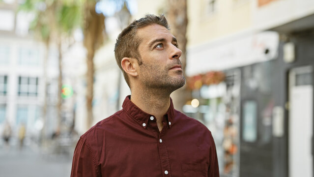 Handsome hispanic man with beard in contemplative pose on urban city street