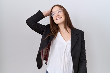 Beautiful brunette woman wearing business jacket and glasses smiling confident touching hair with hand up gesture, posing attractive and fashionable