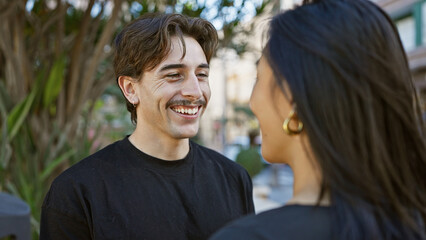 Obraz premium A smiling interracial couple enjoying a sunny day outdoors on a city street, embodying love and togetherness.