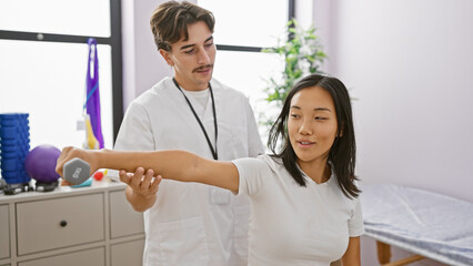 Fototapeta premium A man therapist assists a woman patient with dumbbell exercises in an indoor rehabilitation clinic.