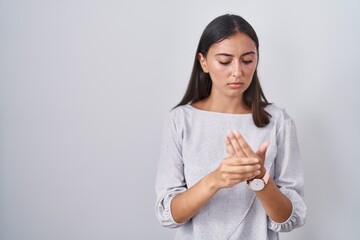 Young hispanic woman standing over white background suffering pain on hands and fingers, arthritis inflammation