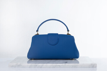 Luxury fashion blue color leather bag on marble and white background in studio
