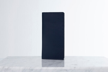 Dark leather wallet for credit cards and money on marble floor and white backdrop in studio