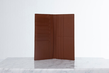 Brown leather men's wallet for credit cards and money on marble floor and white backdrop in studio