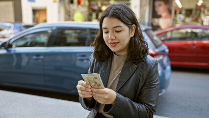 Young hispanic woman examines brazilian currency on a bustling city street.