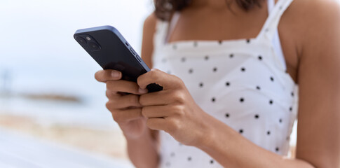 Young african american woman using smartphone at seaside
