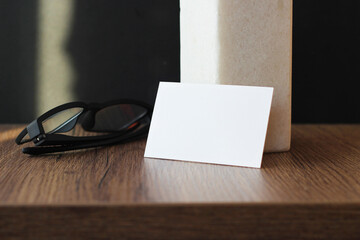 Blank business card mockup with glasses on wooden table background. Mock up for branding identity....