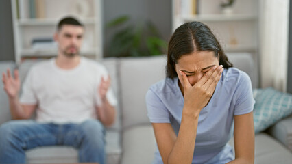 Distressed beautiful couple arguing and crying on the relaxed sofa at home, their love stressed and...