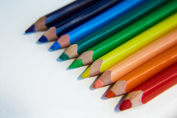 Сolored pencils lie in a row. Colors of the rainbow. Learning, drawing, school, classes, art. Office supplies, coloring books, sharpeners, pencil cases. Art therapy, psychology, rehabilitation.