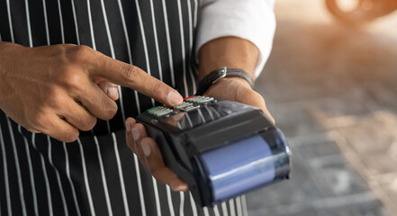 close up waiter man hand press on contactless payment reader to checking about payment order in the cafe for technology transaction concept
