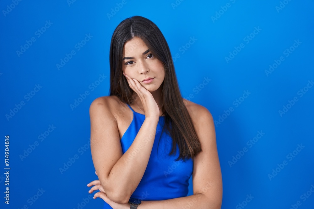 Poster hispanic woman standing over blue background thinking looking tired and bored with depression proble