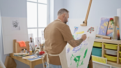 Handsome young man artist intensely drawing at his relaxed art studio, a creativity class bursting...
