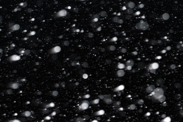 night snowfall. blurry white snowflakes on a black background