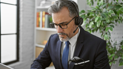 Attractive grey-haired hispanic man, a young business professional, engrossed in work indoors....