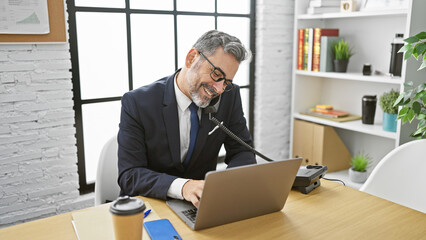 Confident grey-haired hispanic man engaged in a business talk over the phone, working online in...