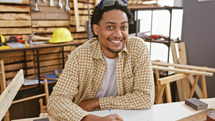 Handsome man with curly hair smiling at his carpentry workshop, reflecting his profession and creativity.