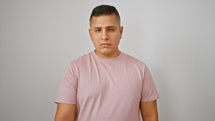 Cool young hispanic man poised in a relaxed lifestyle portrait, standing with a serious expression,...