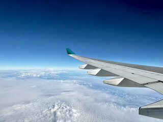 Aerial photography of clear blue sky with different shape of clouds and colours from sunlight dispersion, seen from airplane window
