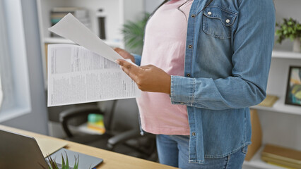 Expecting young worker, pregnant businesswoman reading documents, tenderly touching her belly,...