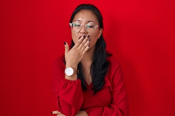 Asian young woman standing over red background bored yawning tired covering mouth with hand. restless and sleepiness.