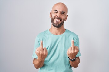 Middle age bald man standing over white background showing middle finger doing fuck you bad...
