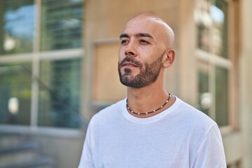 Obraz premium Young bald man looking to the side with serious expression at street