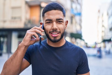 Young latin man smiling confident talking on the smartphone at street
