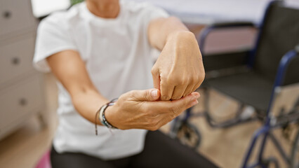 A middle-aged woman performs wrist exercises in a rehabilitation clinic, showcasing healthcare in an indoor setting.