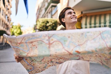 Young caucasian man smiling confident holding city map at street