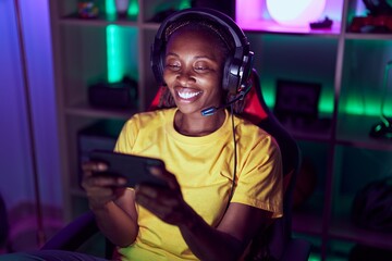African american woman streamer playing video game using smartphone at gaming room