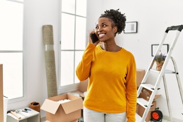 African american woman talking on smartphone standing at new home