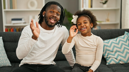 African american father and daughter smiling confident sitting on sofa speaking at home