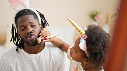 African american father and daughter wearing funny diadem playing with makeup at bedroom