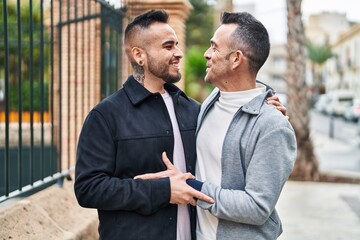 Two men couple smiling confident hugging each other at street