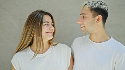 Beautiful couple smiling confident looking each other over isolated white background