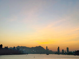 Fototapeta premium Maginificent Hong Kong evening skyline with romantic sunset view from Kai Tak Cruise Ferry Terminal Park, rooftop level, seeing the ferries, harbour, strait, and Hong Kong skyscrapers