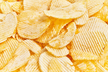 Close-up of crispy golden potato chips filling the frame, suggesting a snack or food theme.