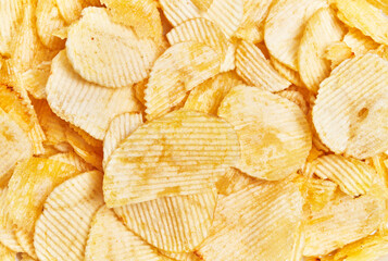 Crispy ridged potato chips cover the frame, suggesting a background texture for snack-related...
