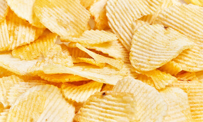 Close-up of many ridged potato chips filling the frame, depicting a concept of snacking or junk food.
