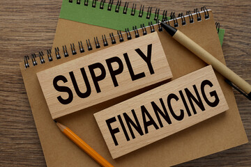 SUPPLY FINANCING text on wooden blocks on a notepad