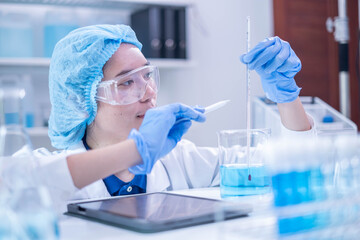 Fototapeta premium Professional woman specialist doctor laboratory white uniform use thermometer temperature on blue liquid in healthcare and medicine experiment equipment with glove care, young adult female scientist