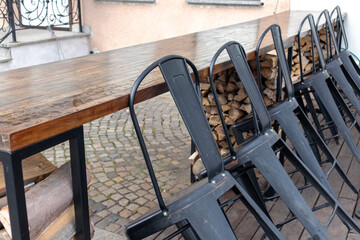 
A wooden table with a row of padded chairs on it in an outdoor cafe